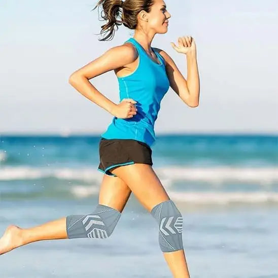 Coureur portant des manchons de compression du genou faisant de l’exercice sur une plage.