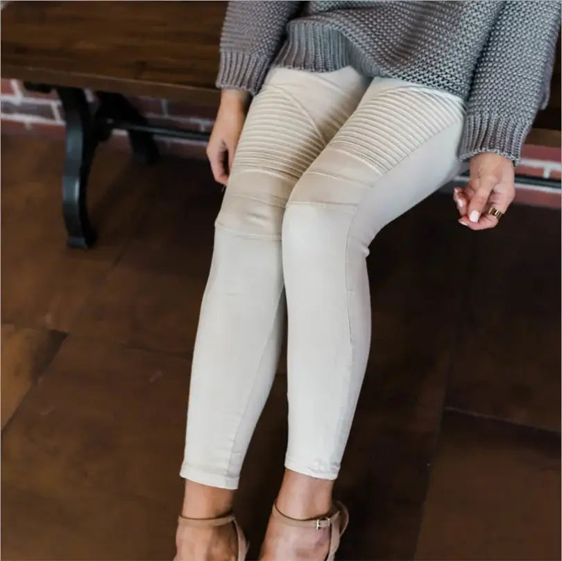 Des leggings blancs côtelés ou des pantalons moulants portés avec un pull gris et des talons à lanières.