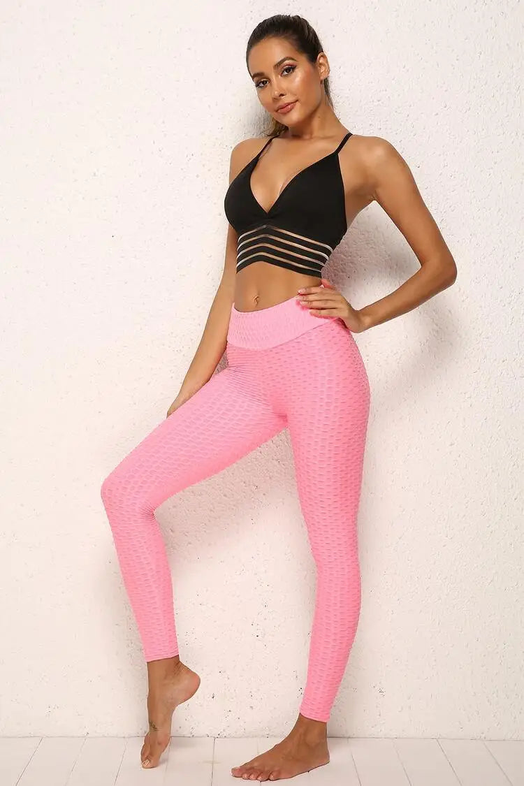 Femme portant des leggings rose vif et un top noir dans une pose de fitness.