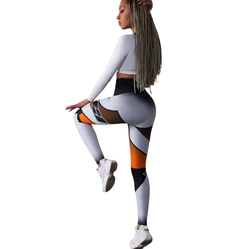 Femme portant un legging de sport coloré et un top blanc, posant avec une jambe levée.
